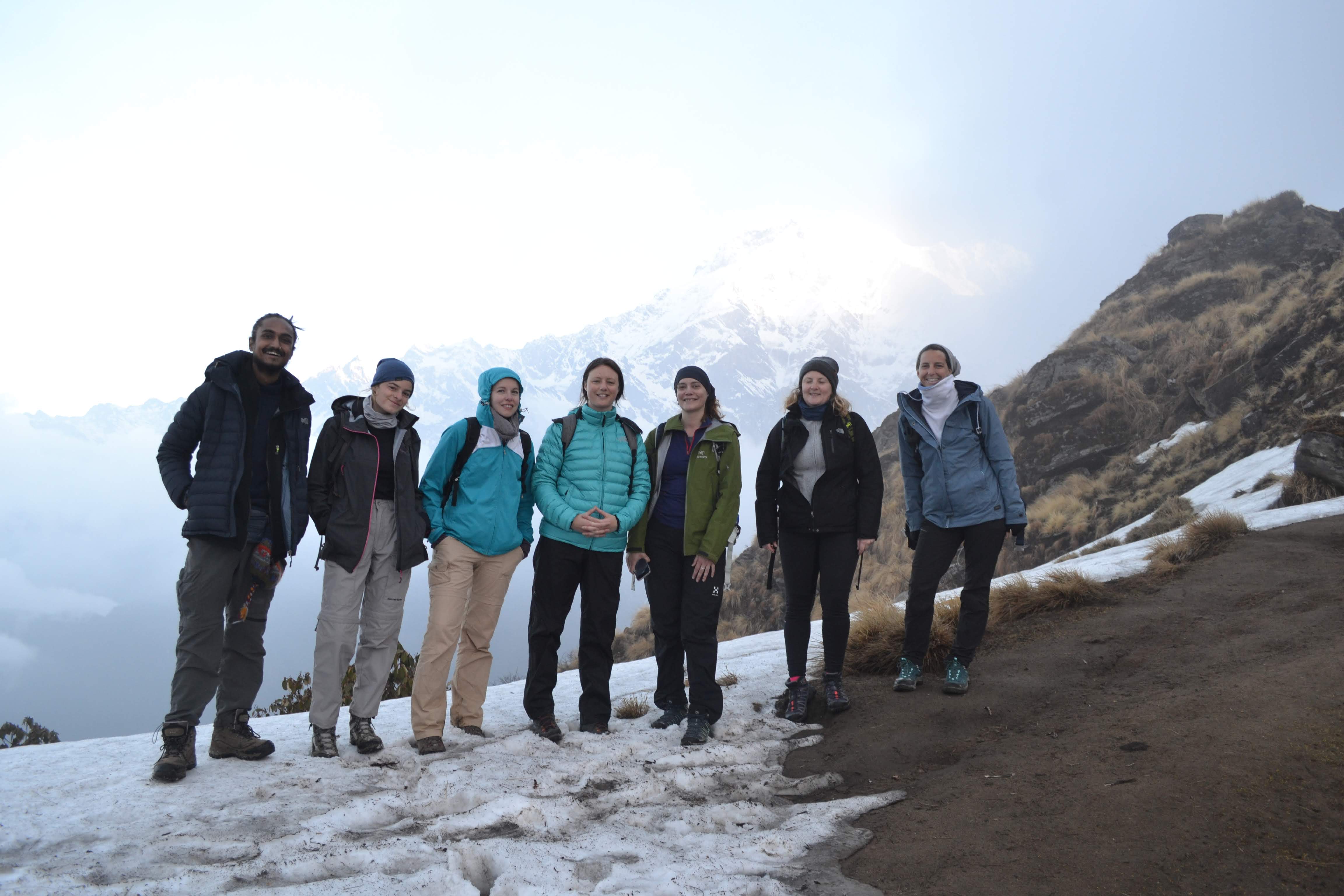 Diverse group standing together at high altitude with snow and mountain backdrop