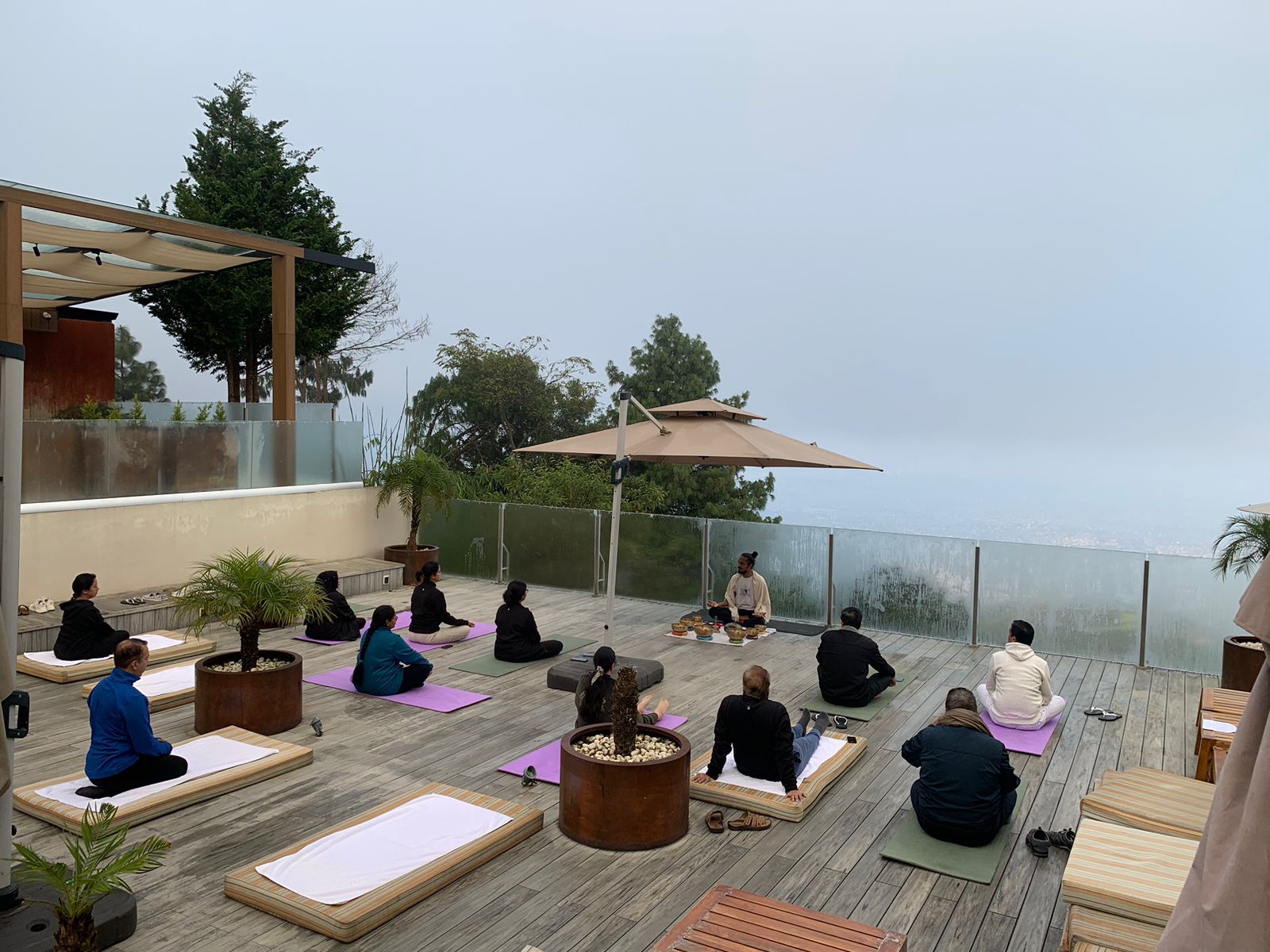 Group meditation circle on rooftop with golden hour light and valley views