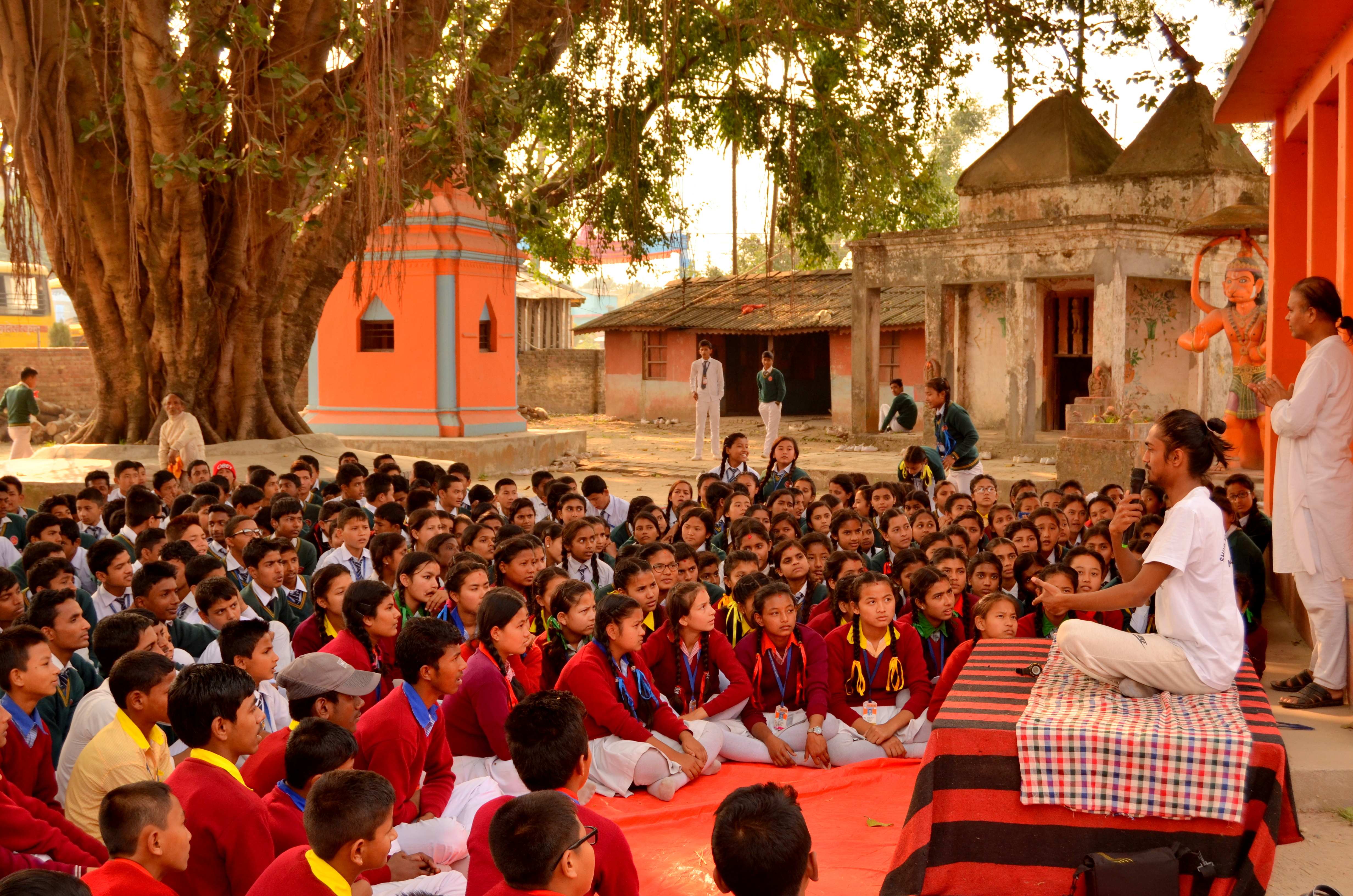 Teaching large gathering of students under ancient banyan tree