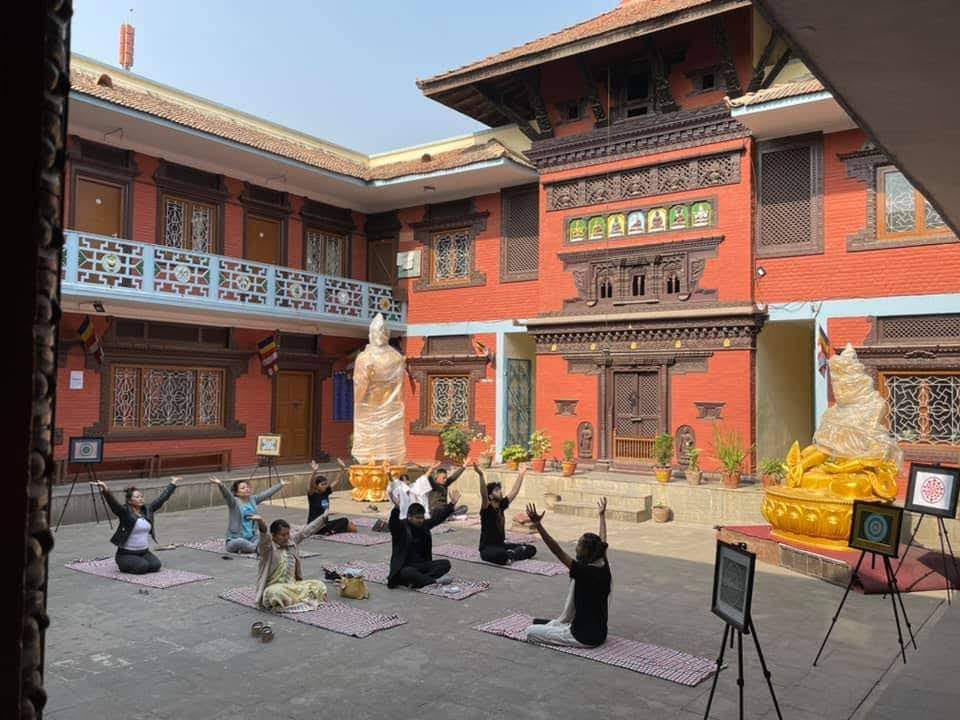 Group yoga practice in sacred Buddhist temple courtyard with golden Buddha